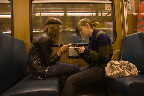 girls sharing headphones